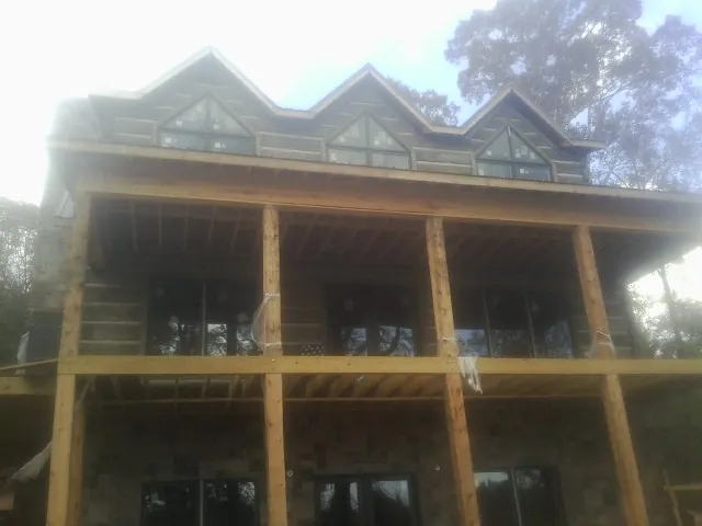 Dormers and porch framing on a large log home under construction — Roof Coating work by our crew in Newbern
