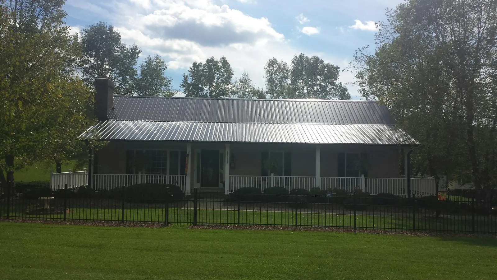 Gray metal roof on a brick ranch with a full width front porch — Gutter Guard Installation work by our crew in Newbern
