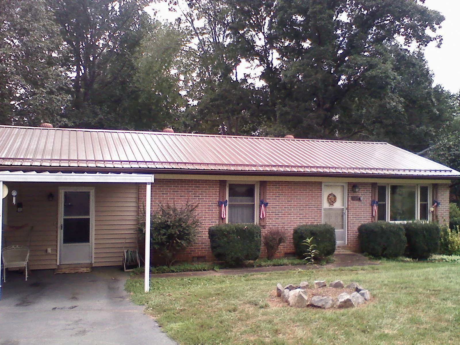 Bronze metal roof and carport on a brick ranch home — Roof Repair work by our crew in Newbern