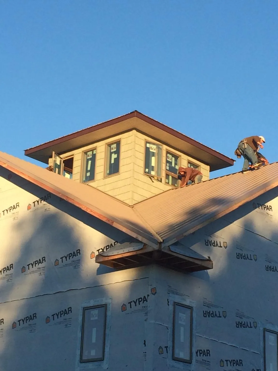 Roofers working around a rooftop cupola on a new metal roof at sunset — Roof Waterproofing in Newbern by Roofing Brothers